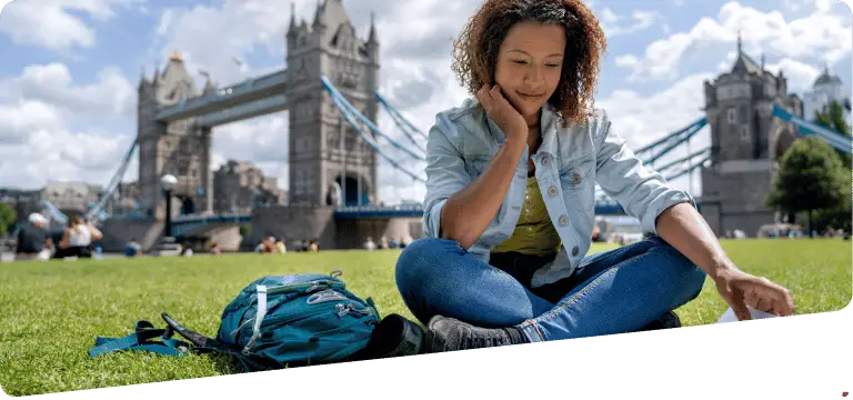 Étudiante lisant assise sur une pelouse devant Tower Bridge à Londres